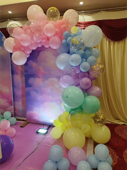 A beautiful pastel-colored organic balloon garland against a dreamy sky backdrop, perfect for a unicorn or fantasy theme.
