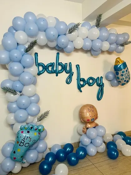 A simple and charming "Baby Boy" decoration. It features a half-arch of blue and white balloons with "It's a Boy" and baby-themed foil balloons.