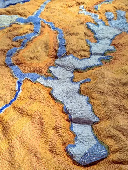 'A Piece of Earth', a textile artwork from our 'Cu+Fibers' exhibition. This piece uses kantha stitching and varied fiber textures to create a topographical map, abstracting a landscape into a tactile surface.