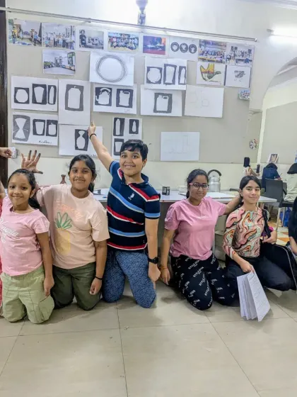 A happy group photo of our students from three different batches. The wall behind them is covered with their work, showcasing the progress they've made in their design fundamental classes.