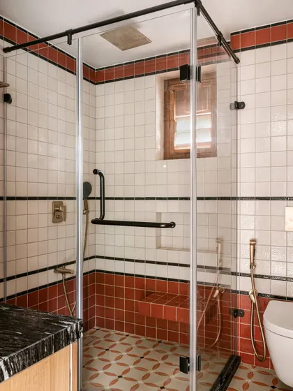 This bathroom in Kolam Pop channels the project's ethos with a rhythmic play of tiles. Patterned floor tiles echo Kolam motifs, while bands of terracotta and black animate the white-tiled walls.