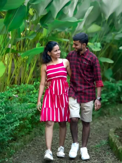 A sweet pre-wedding photo of a couple walking together through a garden, sharing a loving glance.