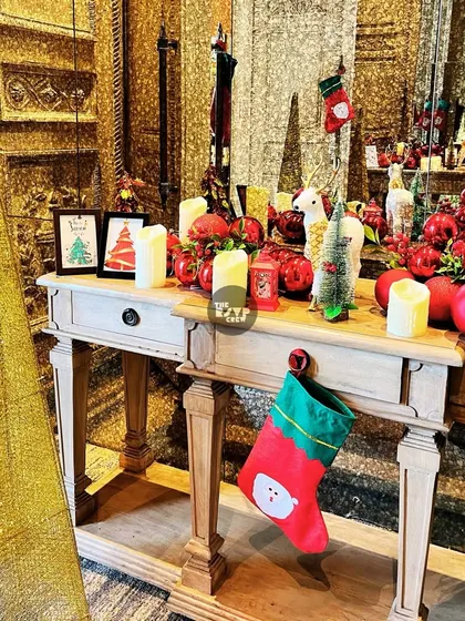 'Tis the season! A console table beautifully decorated for a Christmas-themed party with stockings, candles, and festive red ornaments.