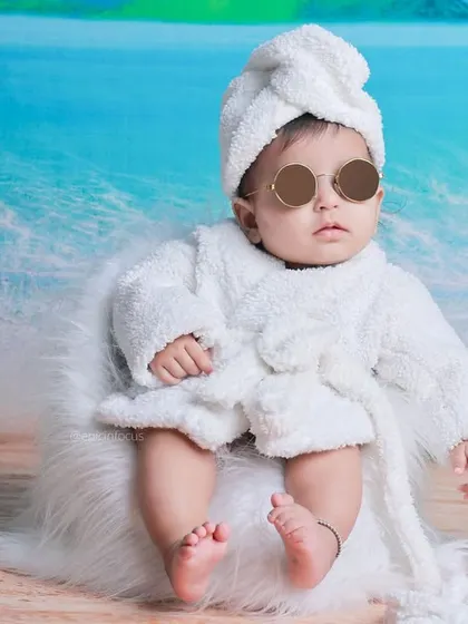The epitome of cool. A baby in a robe and sunglasses brings a humorous and stylish vibe to this beach-themed studio shoot.