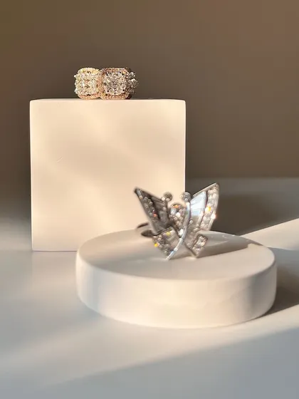 Delicate yet striking rings are just what you need for any event. This photo showcases a modern butterfly ring and a classic double halo ring, both crafted to last forever.