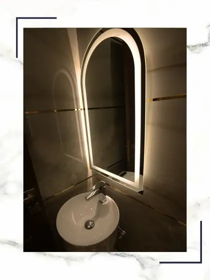 Luxury, lather, and a little indulgence. The arched, backlit mirror serves as a stunning focal point in this elegantly designed powder room.