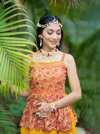 A beautiful portrait of the bride at her Haldi ceremony, showcasing her intricate floral jewelry and traditional attire.