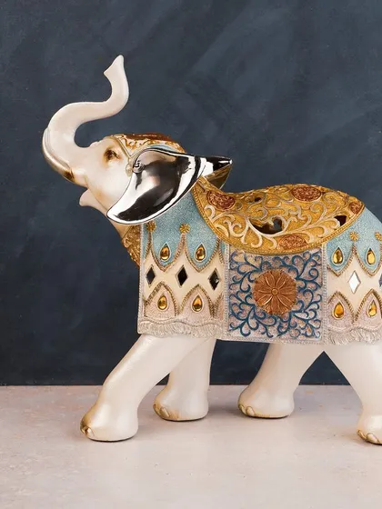 This ornate elephant sculpture is decorated with a beautiful blue and gold blanket, giving it a regal, ceremonial feel. It's a piece that celebrates traditional artistry and majestic beauty.