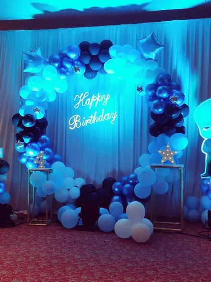 A cool blue and black Boss Baby theme for a 4th birthday, featuring a balloon ring, a light-up number, and a glowing character cutout.