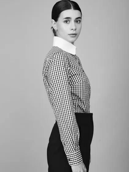 A clean and crisp black and white fashion portrait. The high-contrast look emphasizes the graphic quality of the gingham shirt and the model's strong profile.