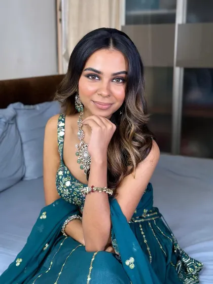 A confident and beautiful pose. The makeup enhances her features and complements her stunning teal outfit perfectly.