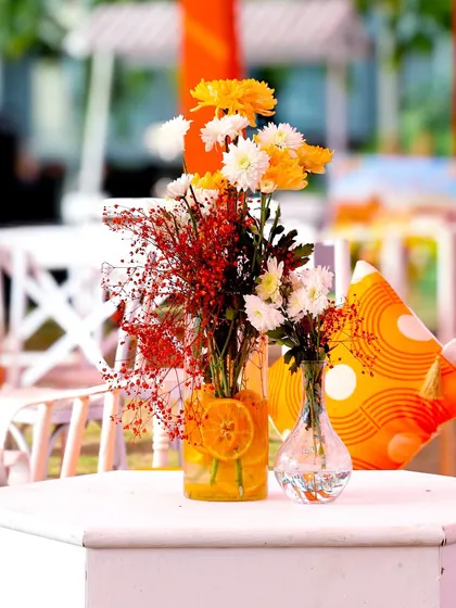 A beautiful centerpiece detail, with fresh flowers and sliced oranges in a clear vase, perfectly capturing the theme's fresh and zesty vibe.