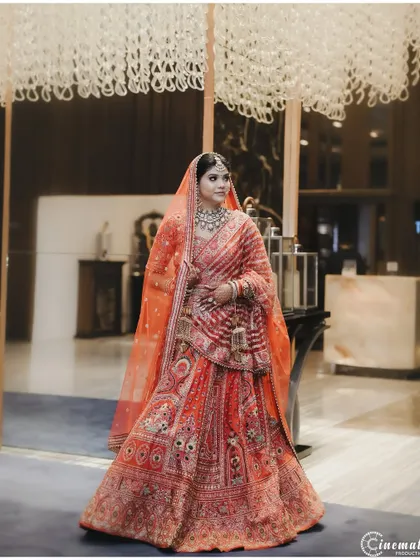 A full-length portrait of the bride in a grand hotel lobby, capturing the opulence of her attire and the location.