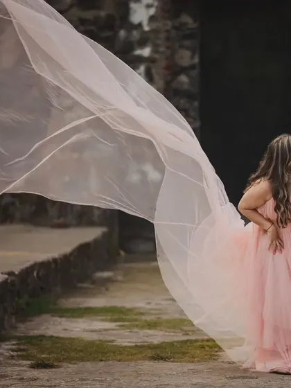 The soft, ethereal quality of this peach net pastel trail gown is just beautiful. The lightweight fabric catches the slightest breeze, creating a dreamy and romantic effect.