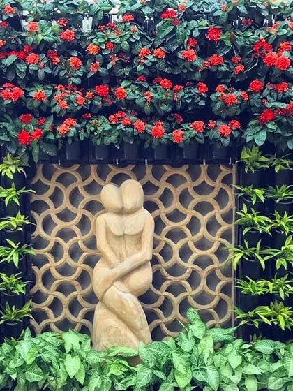 A vertical garden can be a work of art. For this home, I designed a living wall that frames a beautiful sculpture, using flowering red Ixora plants to create a stunning, high-impact centerpiece that feels both natural and elegant.