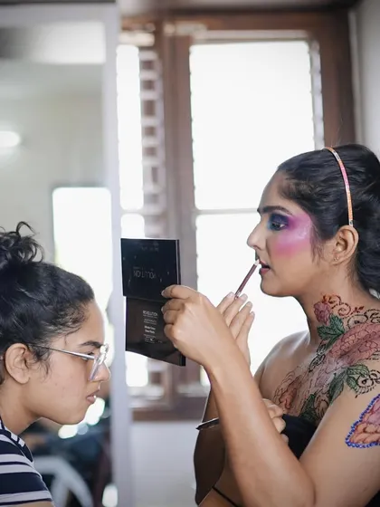 A candid moment from our creative photoshoot, showing the model touching up her makeup while wearing the colored henna body art.