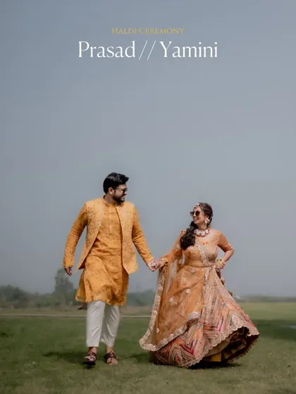 A beautiful wide shot of the couple walking in a field after their Haldi ceremony, capturing a sense of freedom and happiness.