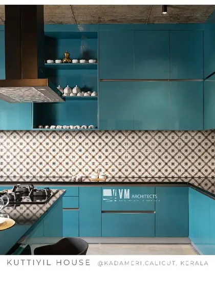 A wide shot of the teal blue kitchen at Kuttiyil House, emphasizing the striking color choice, patterned tiles, and modern appliances.