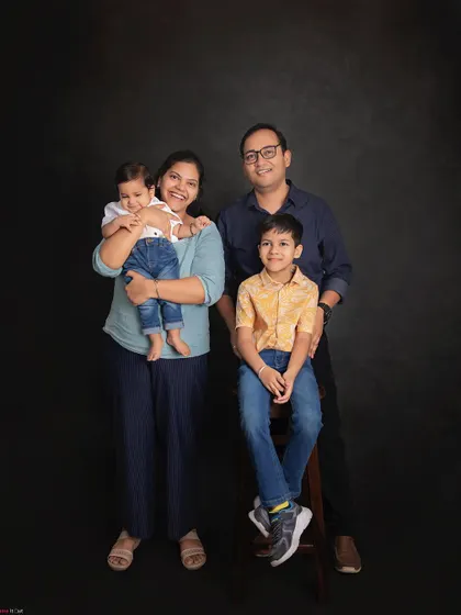 A picture-perfect family of four. This classic studio portrait with a simple dark background puts all the focus on the family's happy smiles and connection.