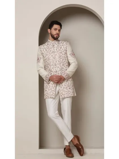An ivory bandhgala jacket intricately detailed with blush peach and rose gold thread embroidery. The delicate jaal work and floral boota motifs create a look of timeless sophistication, perfect for a daytime wedding or elegant formal event.