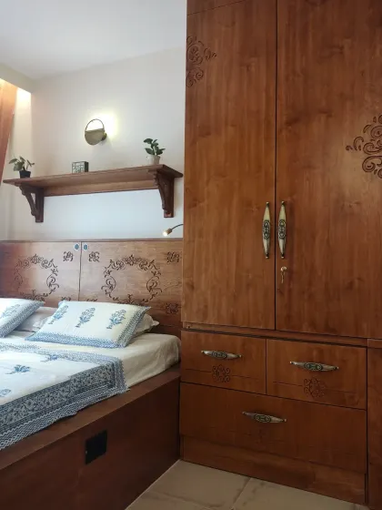 The carved headboard and wardrobe in the Sampada Home bedroom, showing how the design elements flow from the bed to the storage units for a unified look.