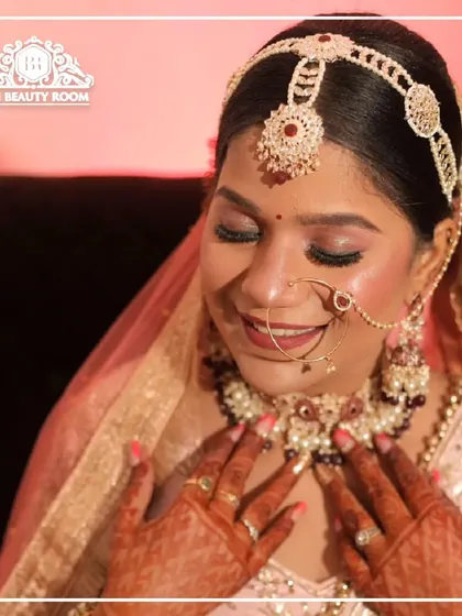 A beautiful, happy moment. The bride's makeup is soft and romantic, with pink tones on her eyes and cheeks to match her pastel lehenga.