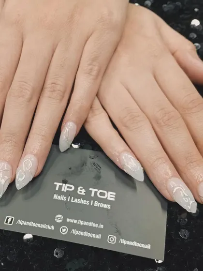 A beautiful example of 3D nail art. These translucent extensions are adorned with delicate white swirls, creating a unique and ethereal effect.