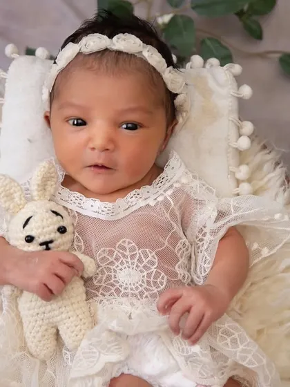 A close-up of the awake baby from the panda theme. She is holding a tiny crocheted bunny, looking right at the camera with her beautiful, curious eyes.