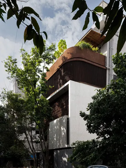 This biophilic residence features a seamless interplay of lime plaster and timber. The white stucco facade provides a clean contrast to vertical timber slats, while layered greenery integrates the villa into its natural context.