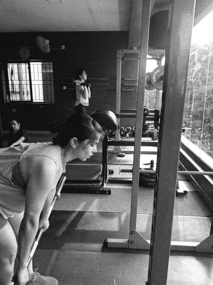 A client performs a bent-over row, captured in a gritty black and white photo that emphasizes the hard work.
