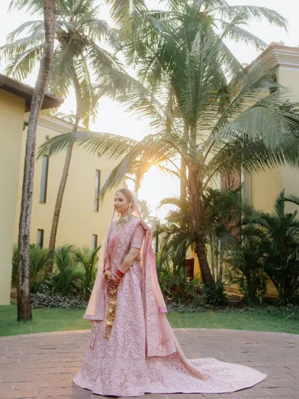 A beautiful bridal portrait of Ashrika, with the golden hour sun filtering through the palm trees behind her, creating a warm and magical glow.