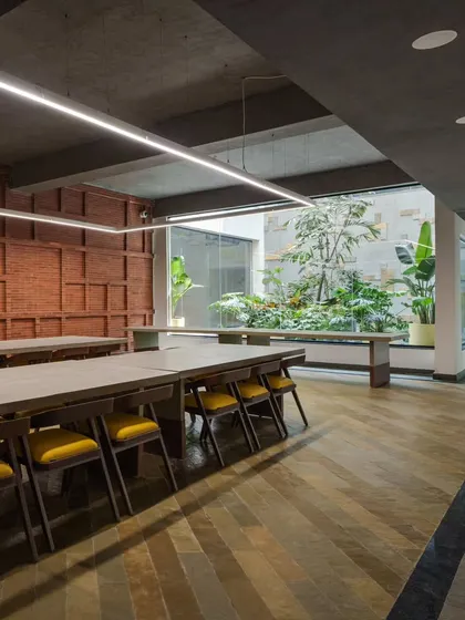 Another view of the VIP dining lounge, showcasing the yellow and grey Kota stone flooring that reflects the color scheme of the adjacent courtyard. The space is illuminated by a linear suspended light, enhancing the industrial aesthetic.