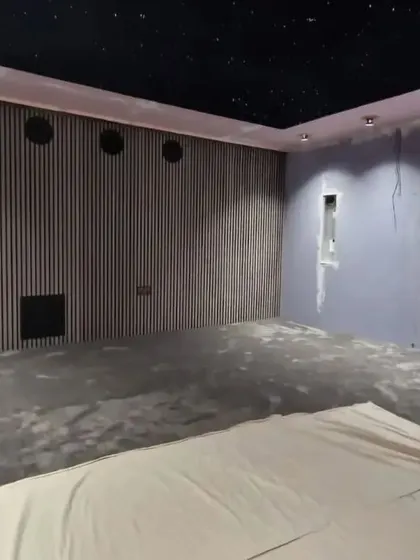 The room during the later stages of construction. The carpet is down, and the wall paneling is being installed.
