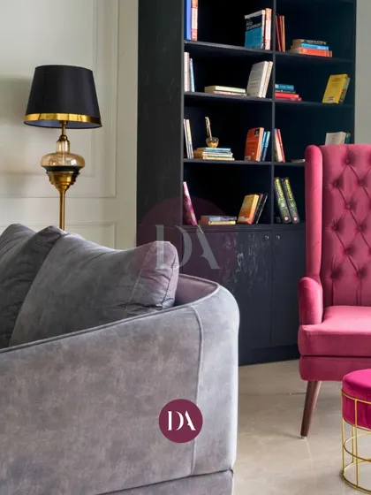 A detail shot showing the relationship between different seating elements in a living room. The grey sofa and magenta armchair create a dynamic color contrast, proving that thoughtful furniture selection is key to a cohesive design.