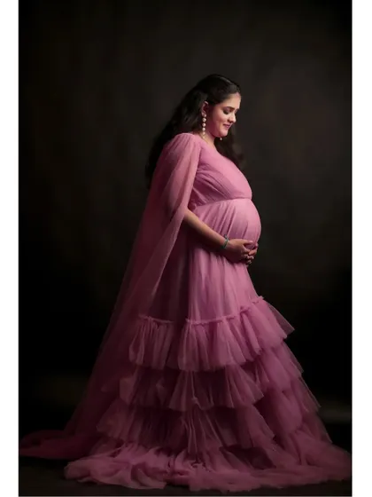 This pink tiered ruffle gown is one of my most popular maternity rentals. The soft tulle and flowing cape sleeves create a delicate, angelic look that photographs beautifully against a dark studio backdrop.