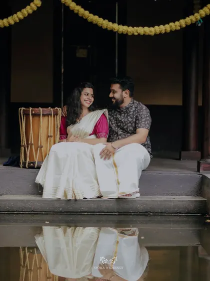 A serene moment by the water, the couple's reflection captured as they sit together on the steps of a traditional house.