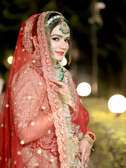 A beautiful bride in a beige and red lehenga, with her makeup perfectly complementing the green in her jewelry.