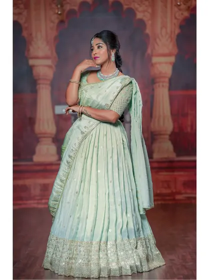 A full-length view of the mint green half-saree, showing the pleated skirt and embroidered border.