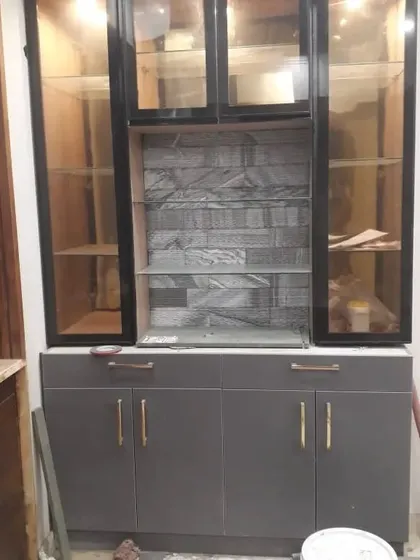 A custom-built crockery unit with a combination of closed cabinets and glass-fronted display shelves, featuring a stone-cladding-style back panel.