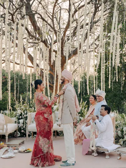An intimate moment from an outdoor wedding, set against a backdrop of hanging tuberoses and elegant, vintage-style furniture. The design was intentionally kept soft and natural to let the beauty of the outdoors shine.