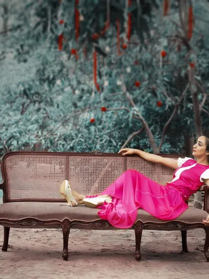 This wide shot showcases the full fuchsia pleated dress in a conceptual setting. The vibrant color and relaxed, flowing fit embody a modern approach to festive Indian dressing.