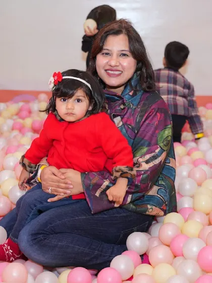 A mother and her young child share a happy moment together in the colorful ball pit.