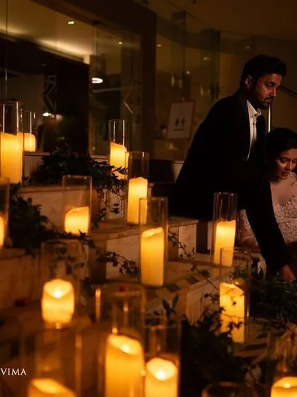 Creating a romantic and cozy atmosphere with soft, delicate lighting. The couple is surrounded by dozens of candles, casting a warm glow that is perfect for intimate reception photos.