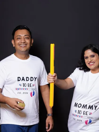 A playful studio photo of an expecting couple in matching "to be" t-shirts, posing with cricket bats. This shows how we can bring your shared passions into the maternity session.