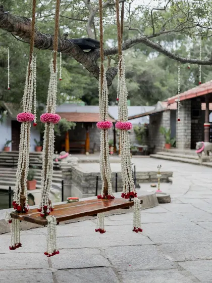 The swing decorated for a naming ceremony, with delicate strings of jasmine and pink flowers, showing its versatility for different family celebrations.