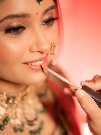 A behind-the-scenes moment, applying the final touch of lipstick to complete the bridal look.