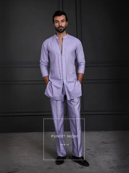 An ensemble where tradition meets modern rhythm. The kurta flows in quiet refinement, its seamless buttons whispering subtlety, paired with a looped tunic and textured bell-bottoms.