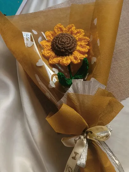 A classic single sunflower bouquet, wrapped in brown paper and clear cellophane with heart prints. A timeless and heartfelt gift.