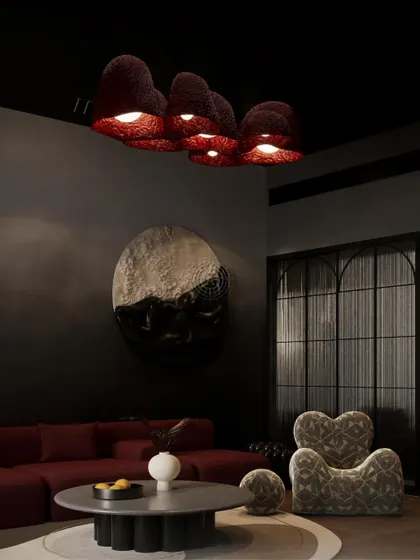 A render for a moody and sophisticated den in a Kolkata home. The design features a deep red sofa, sculptural furniture, and unique, textured ceiling lights to create a cozy yet dramatic atmosphere.
