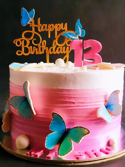 A dreamy ombre cake in shades of pink, decorated with beautiful blue butterflies for a 13th birthday.